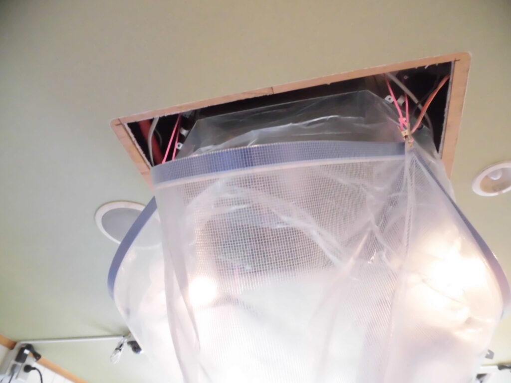 神戸市兵庫区の工場で業務用エアコンクリーニング｜天井エアコン分解後に専用カバーで養生し高圧洗浄準備中